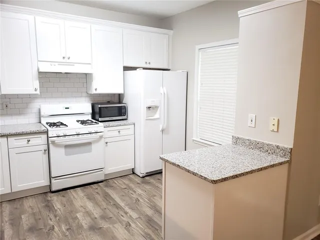 a kitchen with granite countertop white cabinets and white appliances