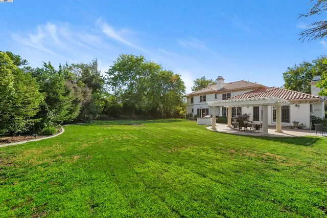 a view of a patio with table and chairs under an umbrella with a big yard