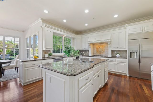 a kitchen with center island wooden floor and a refrigerator