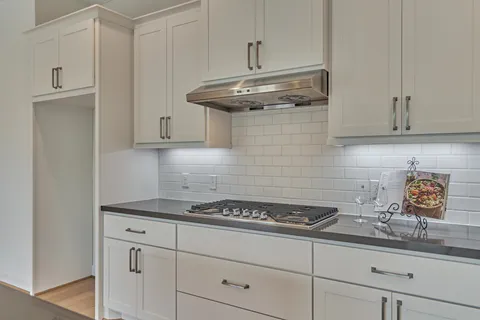 a kitchen with granite countertop stainless steel appliances white cabinets and a sink