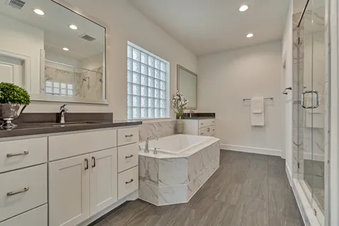 a spacious bathroom with a double vanity sink a mirror and a bathtub