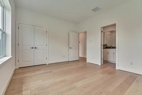 a view of an empty room with wooden floor and closet
