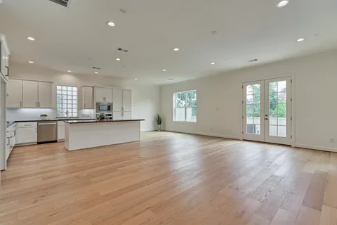 a view of an empty room with kitchen view and a window