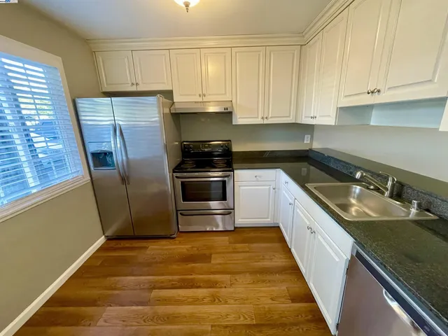 a kitchen with granite countertop a sink stove and refrigerator