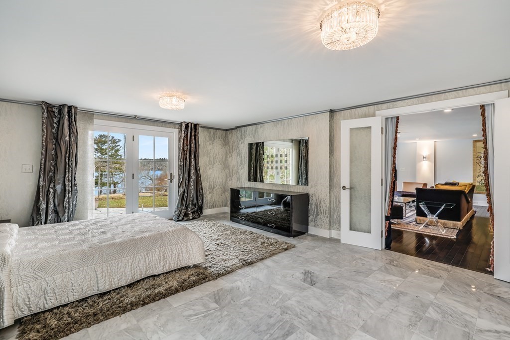 75 Great Hill Road Sandwich, MA 02563 - Photo 19 of 42 a spacious bedroom with a large bed and a chandelier