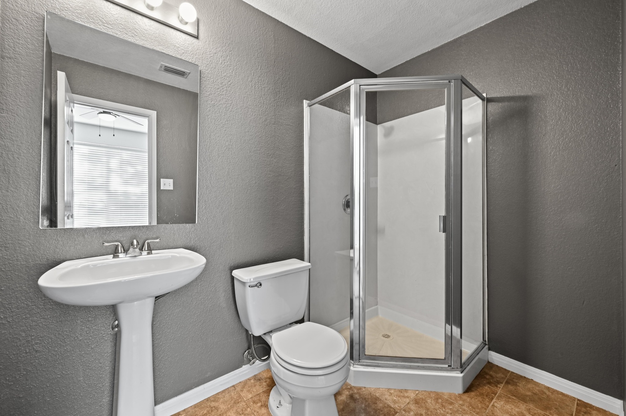 198 Valruth Drive Kyle, TX 78640 - Photo 11 of 32 Bathroom featuring a textured wall, a shower stall, and tile patterned floors