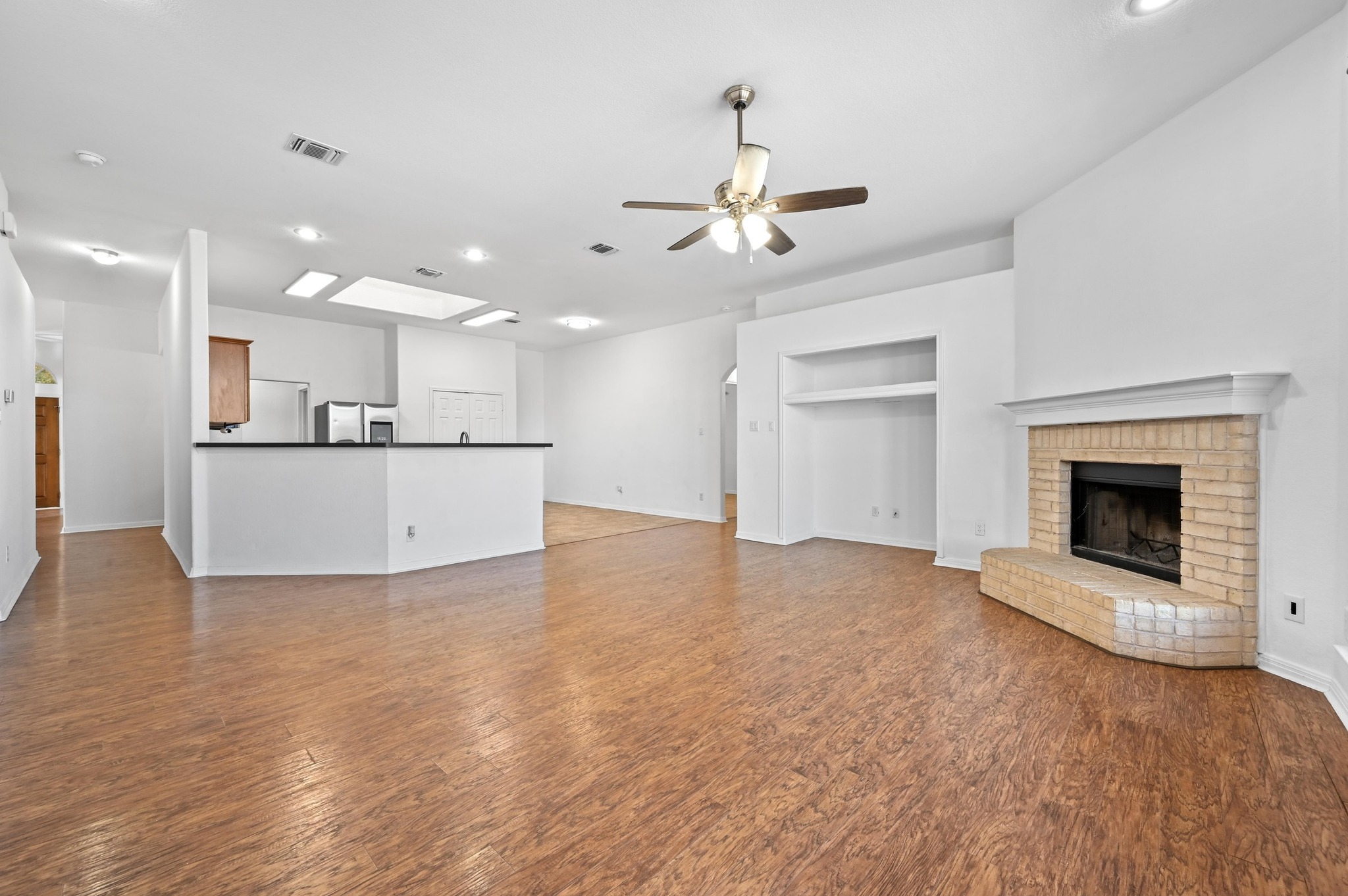 198 Valruth Drive Kyle, TX 78640 - Photo 13 of 32 Unfurnished living room featuring recessed lighting, a brick fireplace, wood finished floors, and a ceiling fan