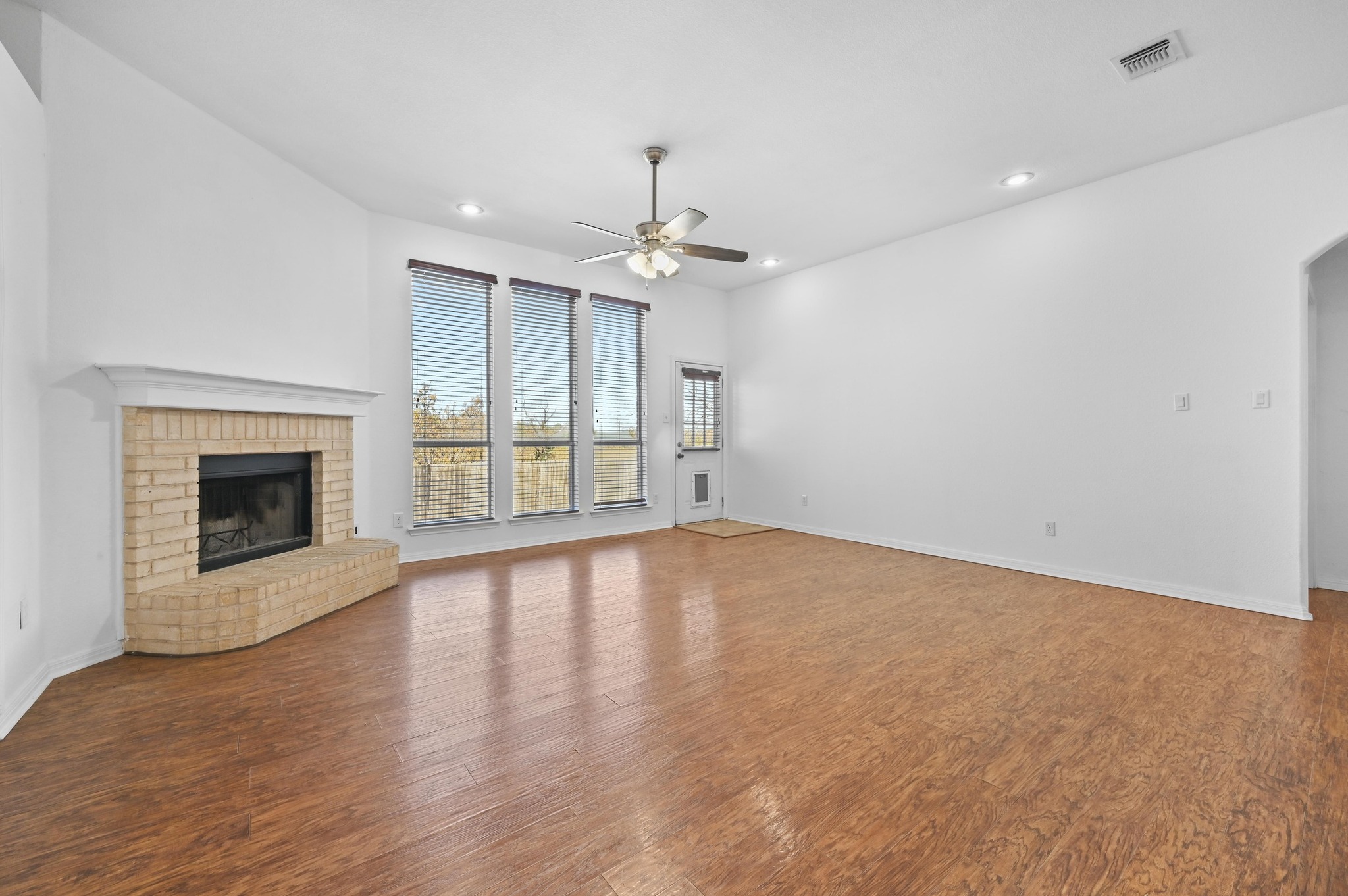 198 Valruth Drive Kyle, TX 78640 - Photo 15 of 32 Unfurnished living room featuring dark wood-style flooring, a brick fireplace, recessed lighting, ceiling fan, and arched walkways