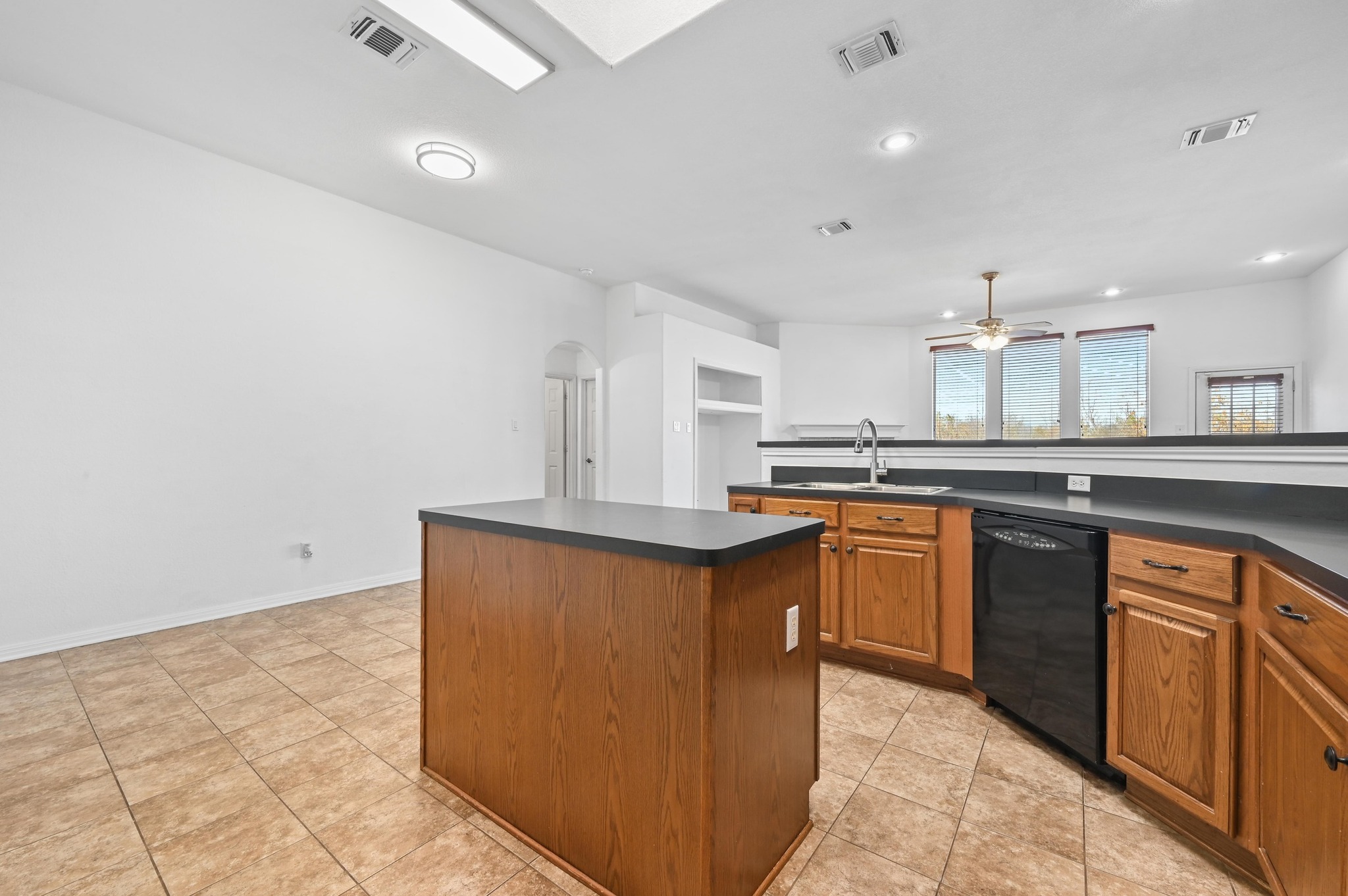 198 Valruth Drive Kyle, TX 78640 - Photo 19 of 32 Kitchen with dark countertops, a center island, arched walkways, brown cabinetry, and recessed lighting