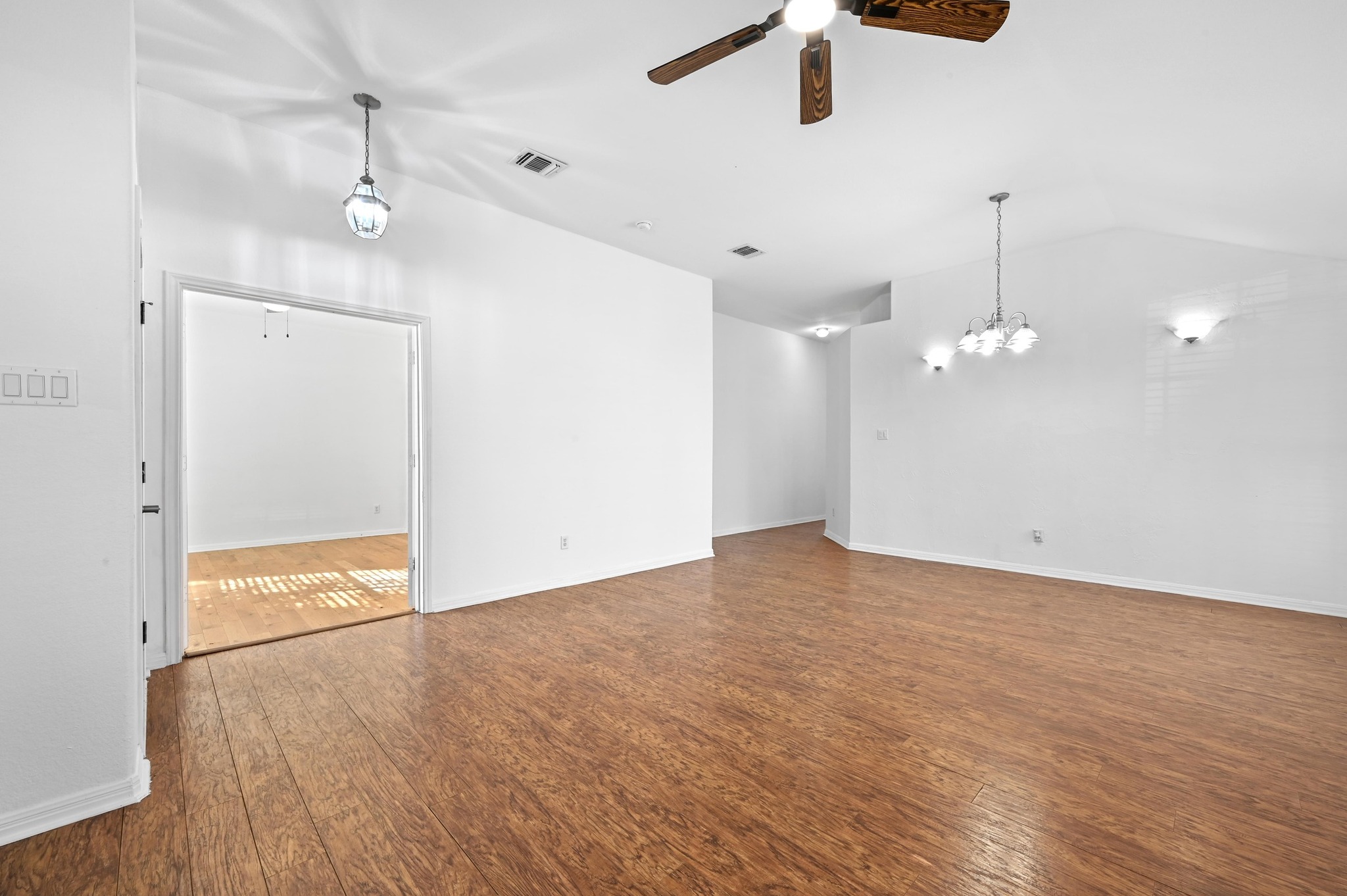 198 Valruth Drive Kyle, TX 78640 - Photo 6 of 32 Unfurnished living room with ceiling fan, dark wood-style floors, lofted ceiling, and a chandelier