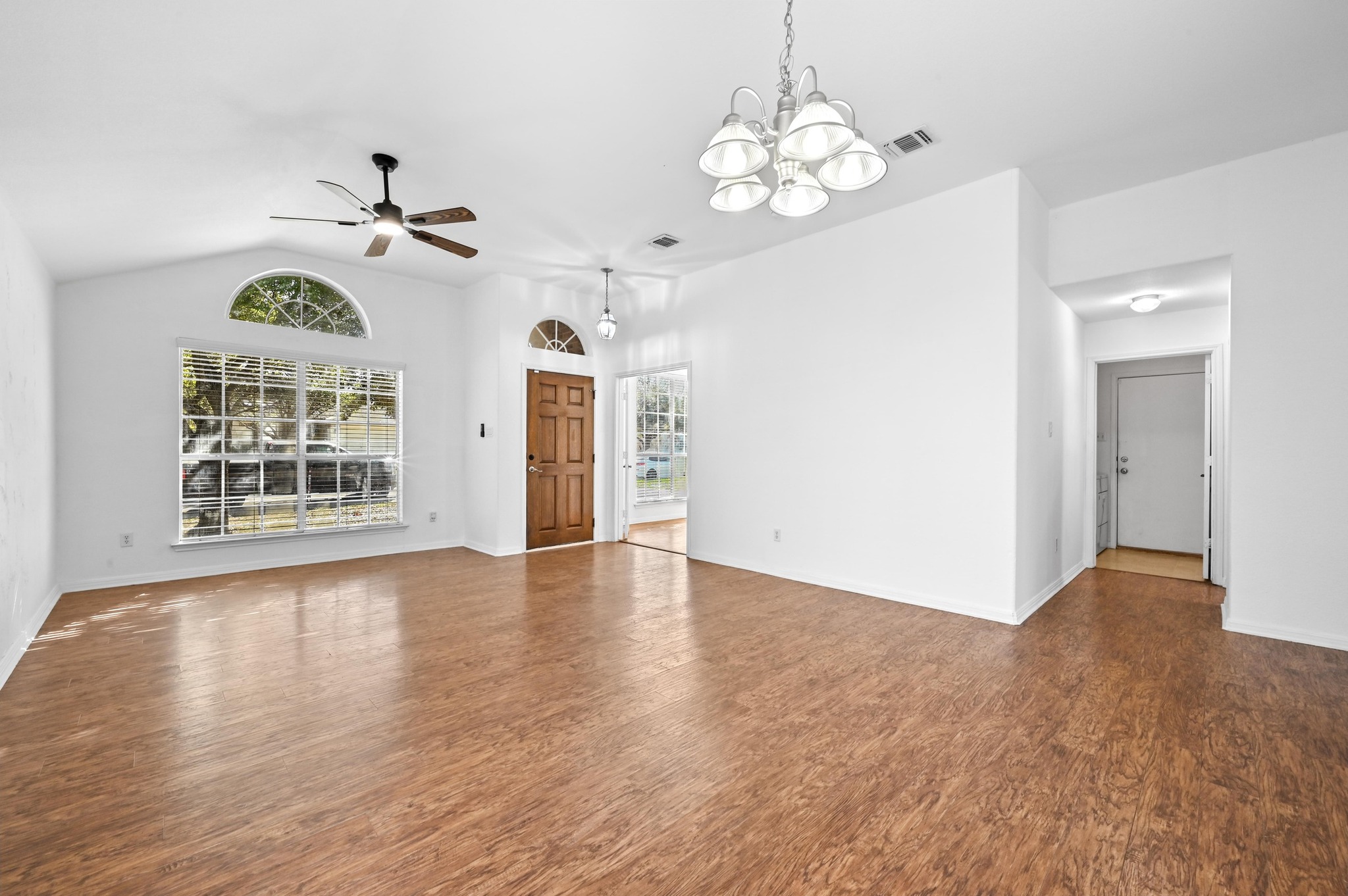 198 Valruth Drive Kyle, TX 78640 - Photo 8 of 32 Unfurnished living room with a chandelier, dark wood-style floors, lofted ceiling, and ceiling fan
