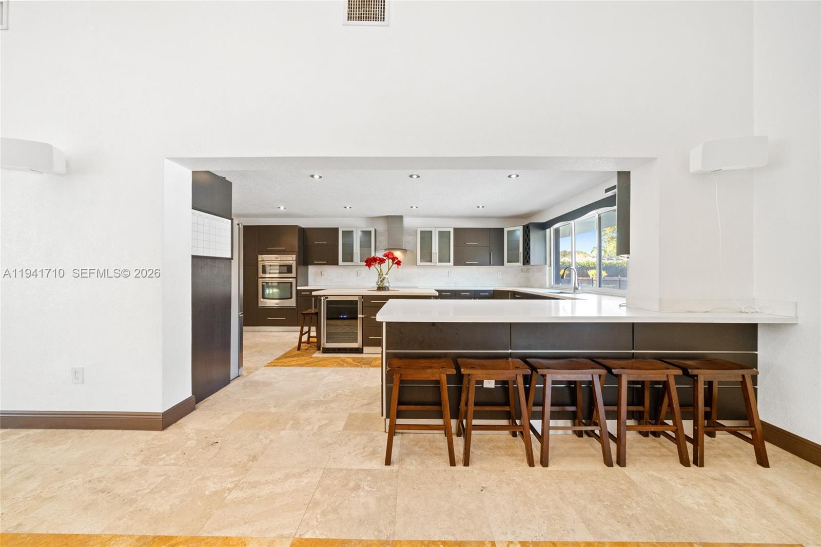 9461 Southwest 128th Street Miami, FL 33176 - Photo 5 of 24 a living room with stainless steel appliances kitchen island a table chairs and a refrigerator