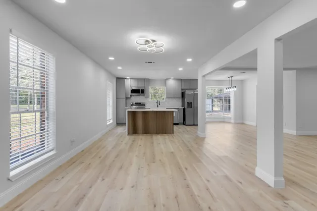 a view of an empty room with a window and kitchen view