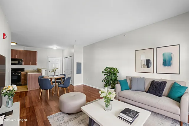 a living room with furniture potted plant and kitchen view