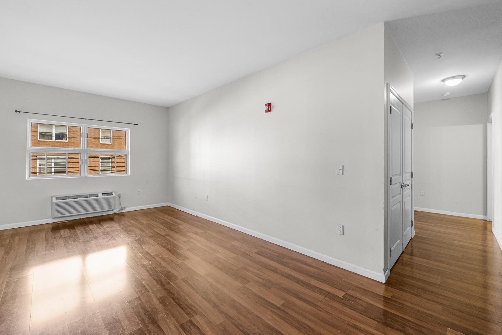 845 Newark Avenue, Unit 3B Jersey City, NJ 07306 - Photo 4 of 26 a view of an empty room with wooden floor and a window