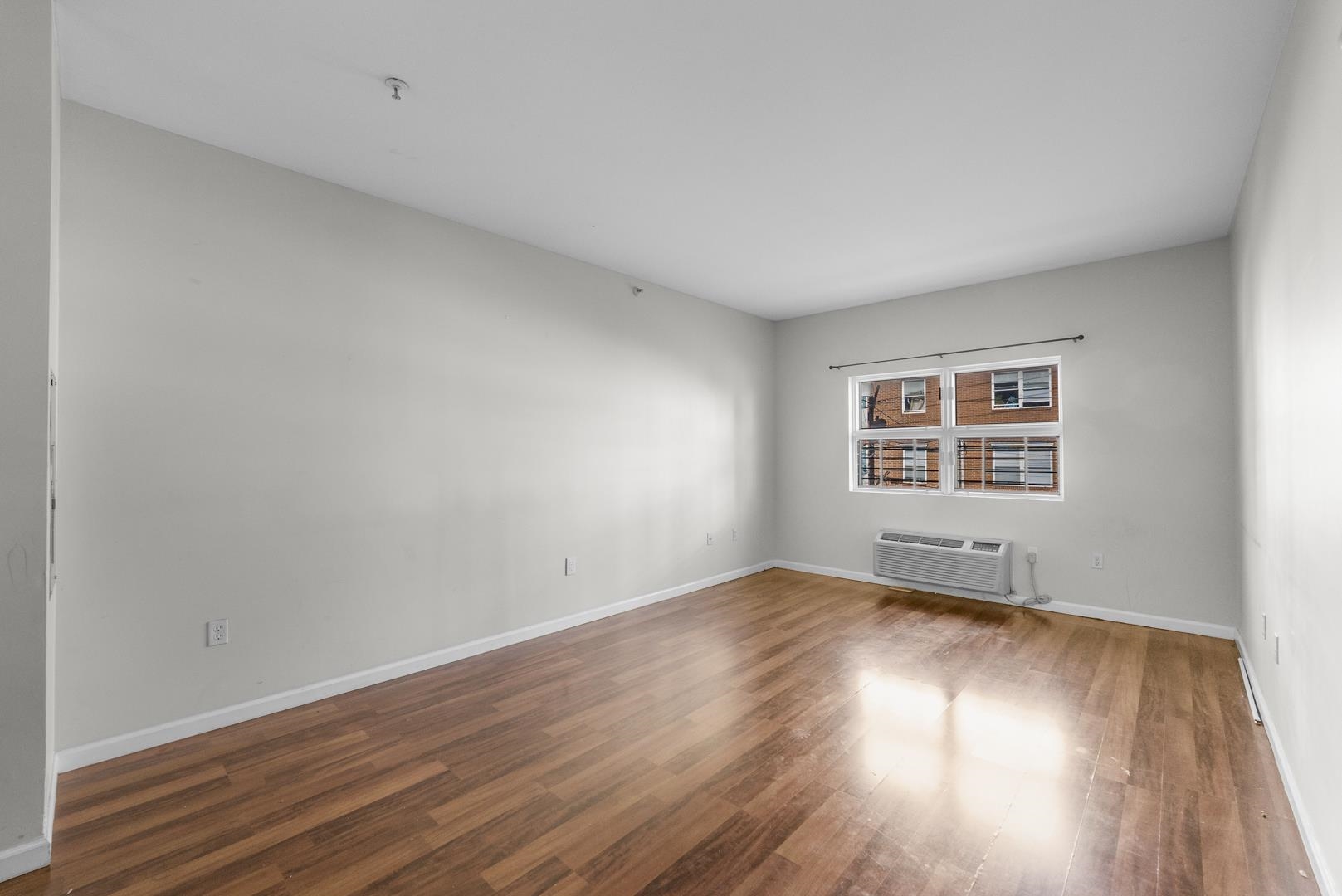 845 Newark Avenue, Unit 3B Jersey City, NJ 07306 - Photo 6 of 26 an empty room with wooden floor and windows