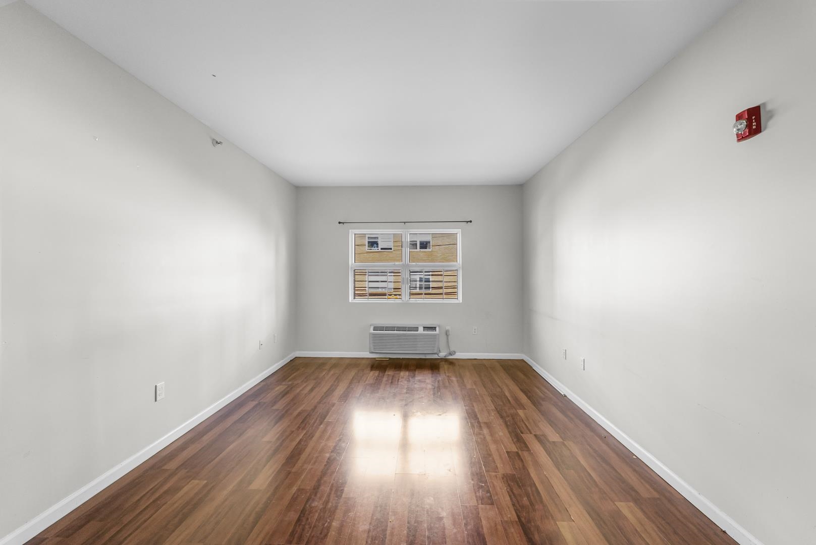 845 Newark Avenue, Unit 3B Jersey City, NJ 07306 - Photo 7 of 26 an empty room with wooden floor and windows