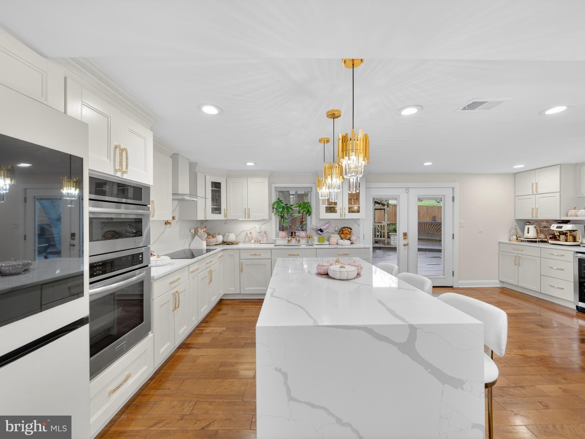 13427 Delaney Road Woodbridge, VA 22193 - Photo 7 of 57 a large white kitchen with kitchen island a stove a sink a refrigerator and cabinets