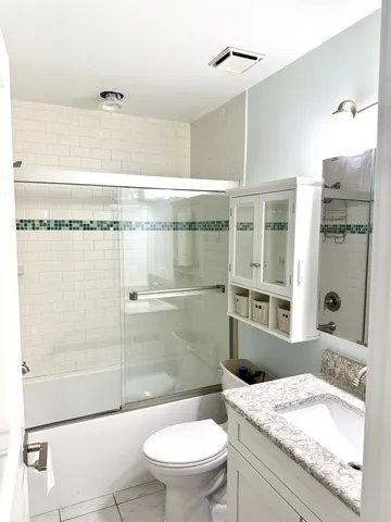 a bathroom with a granite countertop sink a toilet and shower