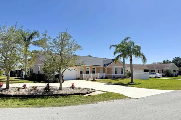 a front view of a house with a yard and palm tree