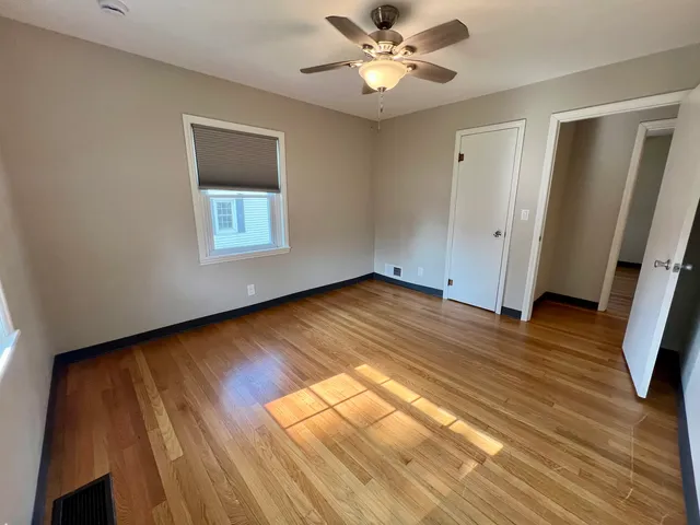 a view of empty room with wooden floor and fan