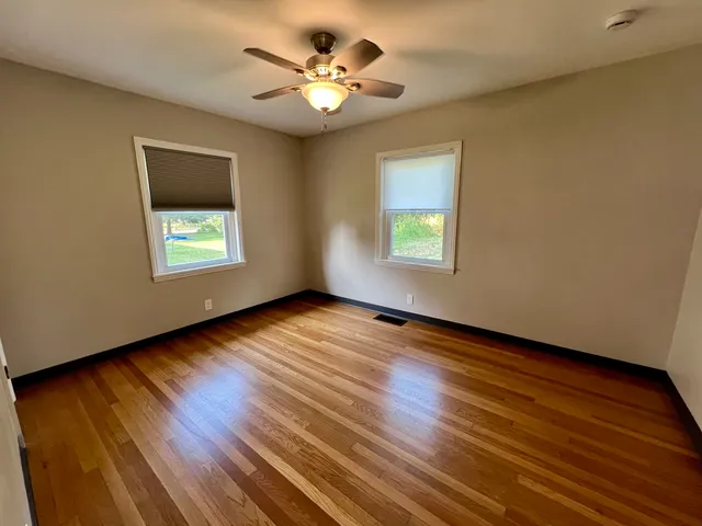 a view of an empty room with a window and wooden floor
