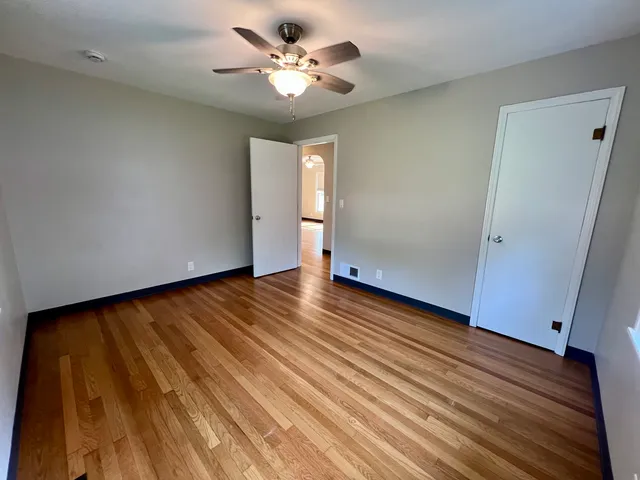 an empty room with wooden floor and ceiling fan