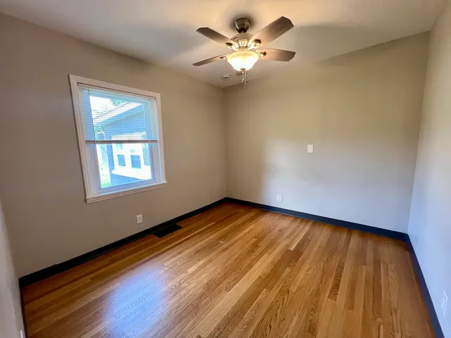 a view of an empty room with a window and wooden floor