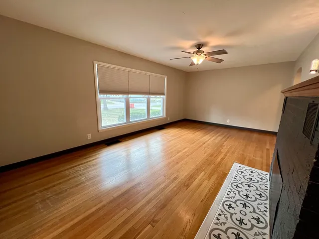 a view of an empty room with window and wooden floor