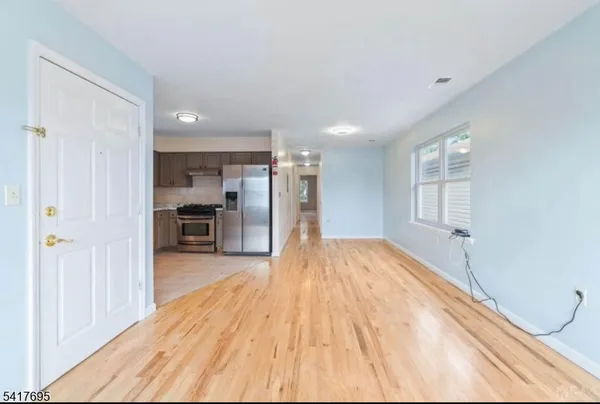 a view of a room with wooden floor and a kitchen