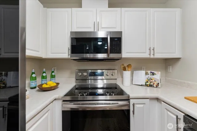 a kitchen with stainless steel appliances granite countertop a stove a white cabinets and a granite counter tops