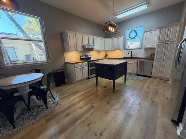 a kitchen with stainless steel appliances granite countertop a sink a stove a refrigerator cabinets and living room view