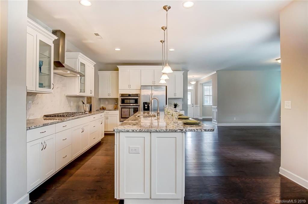 1280 Independence Street, Unit 58 Tega Cay, SC 29708 - Photo 9 of 31 a kitchen with stainless steel appliances kitchen island granite countertop a stove a sink and white cabinets with wooden floor