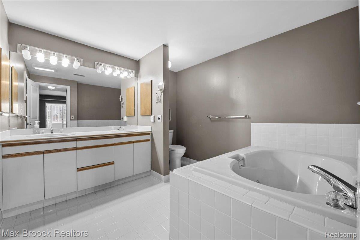 969 GreenView Court, Unit 42 Rochester, MI 48307 - Photo 19 of 41 Bathroom with double vanity, a tub with jets, and light tile patterned floors