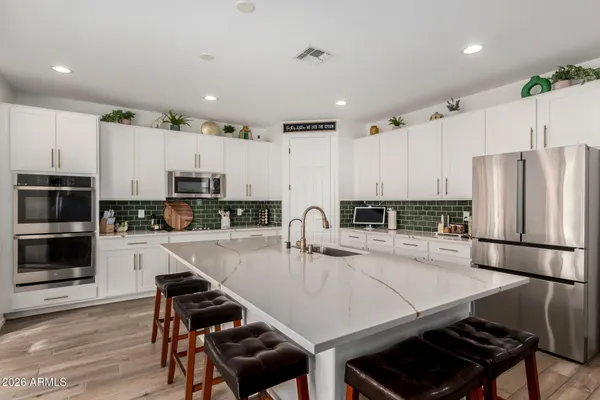 a kitchen with kitchen island a stove a sink a refrigerator and white cabinets with wooden floor