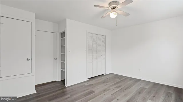 an empty room with wooden floor ceiling fan and window