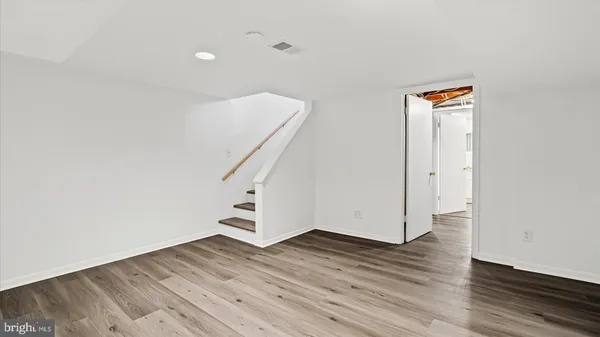 an empty room with wooden floor and stairs