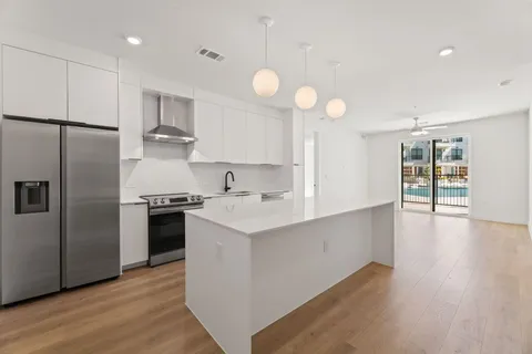 a kitchen with stainless steel appliances a sink a stove a refrigerator cabinets and wooden floor