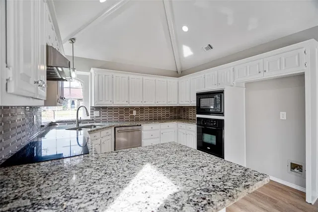 a kitchen with granite countertop a refrigerator stove top oven and sink