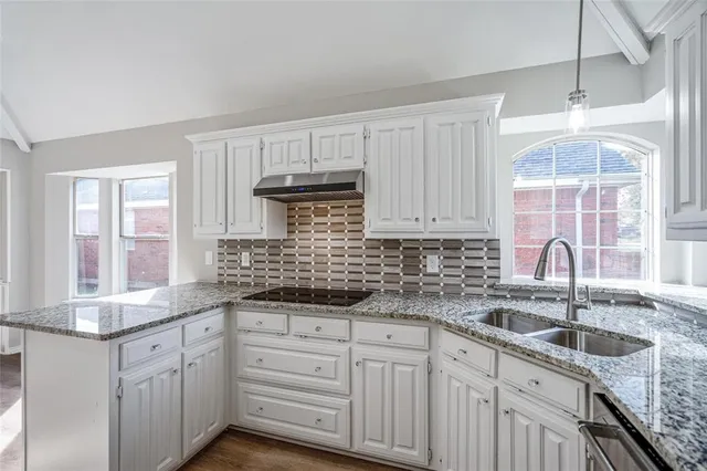 a kitchen with granite countertop a sink stainless steel appliances and cabinets