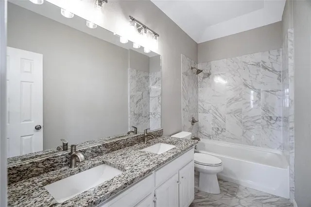 a bathroom with a granite countertop sink a mirror and a bathtub