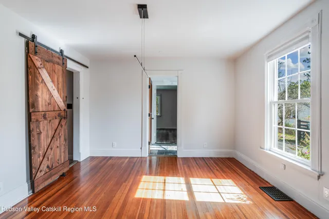 a view of empty room with wooden floor and fan