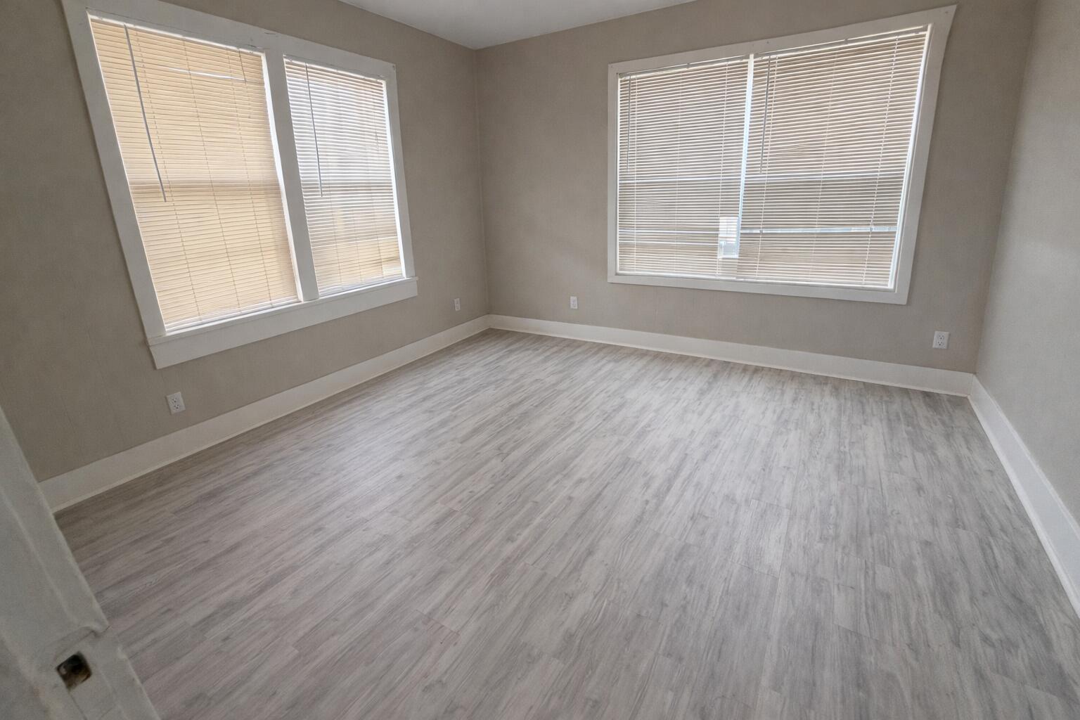 2410 Fisher Street Plainview, TX 79072 - Photo 4 of 8 an empty room with wooden floor and windows