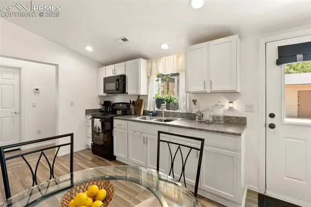 a kitchen with granite countertop a stove a sink and a refrigerator
