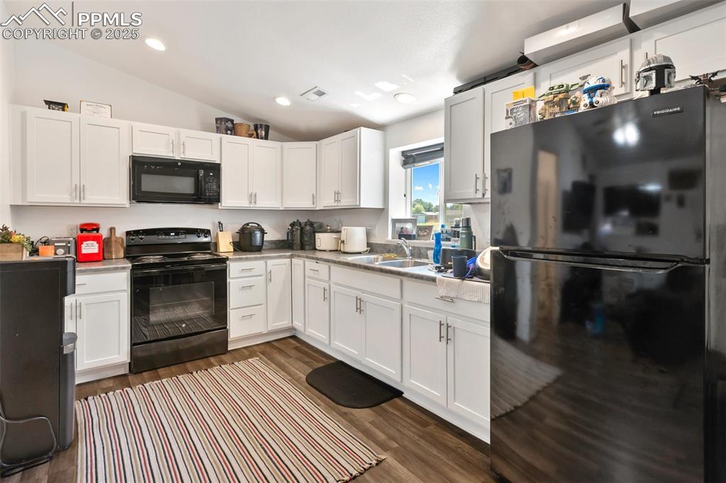 303 East 7th Street Florence, CO 81226 - Photo 28 of 39 a kitchen with granite countertop a refrigerator oven a sink dishwasher and white cabinets with wooden floor