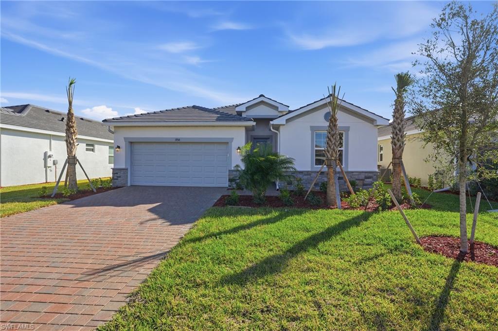 Ranch-style home with stone siding, stucco siding, decorative driveway, and a garage