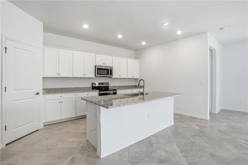 3958 Button Sage Road Alva, FL 33920 - Photo 9 of 50 a kitchen with stainless steel appliances granite countertop a sink a stove a refrigerator and cabinets