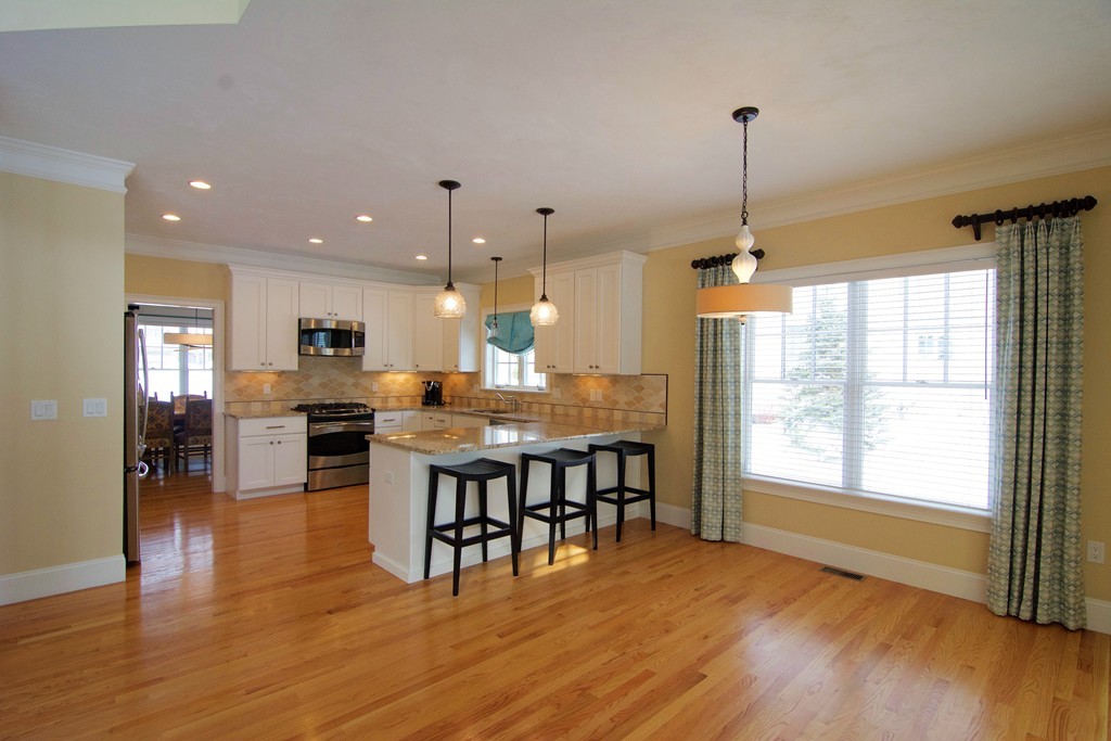 30 Nobscot Road, Unit 24 Sudbury, MA 01776 - Photo 6 of 24 a open kitchen with stainless steel appliances granite countertop wooden floor dining table and chairs