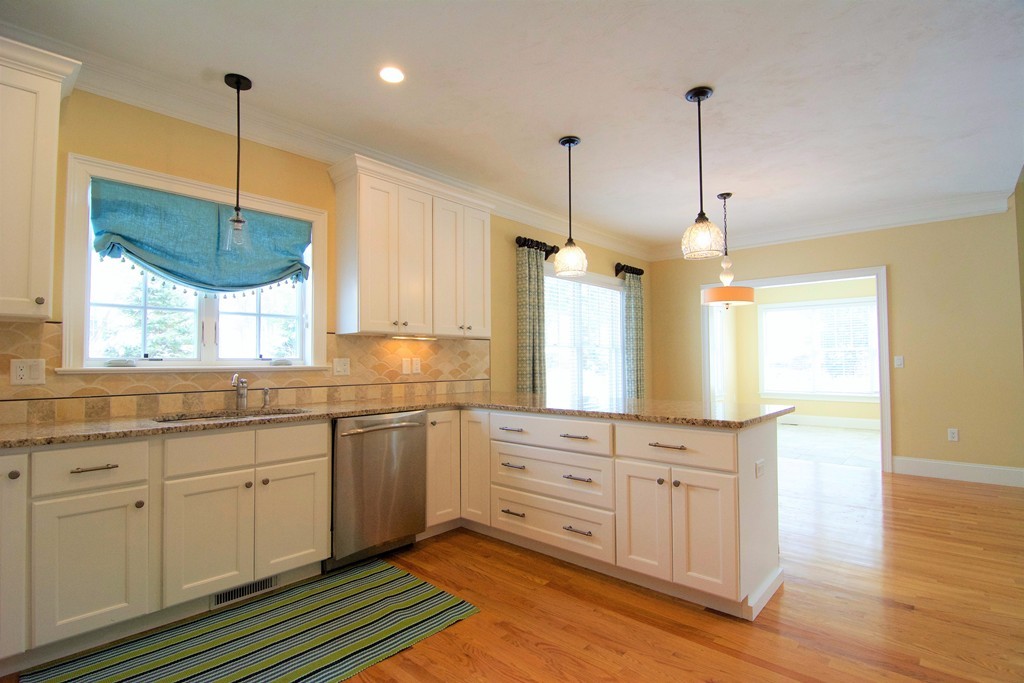 30 Nobscot Road, Unit 24 Sudbury, MA 01776 - Photo 7 of 24 a large kitchen with cabinets a sink dishwasher a dining table and chairs with wooden floor