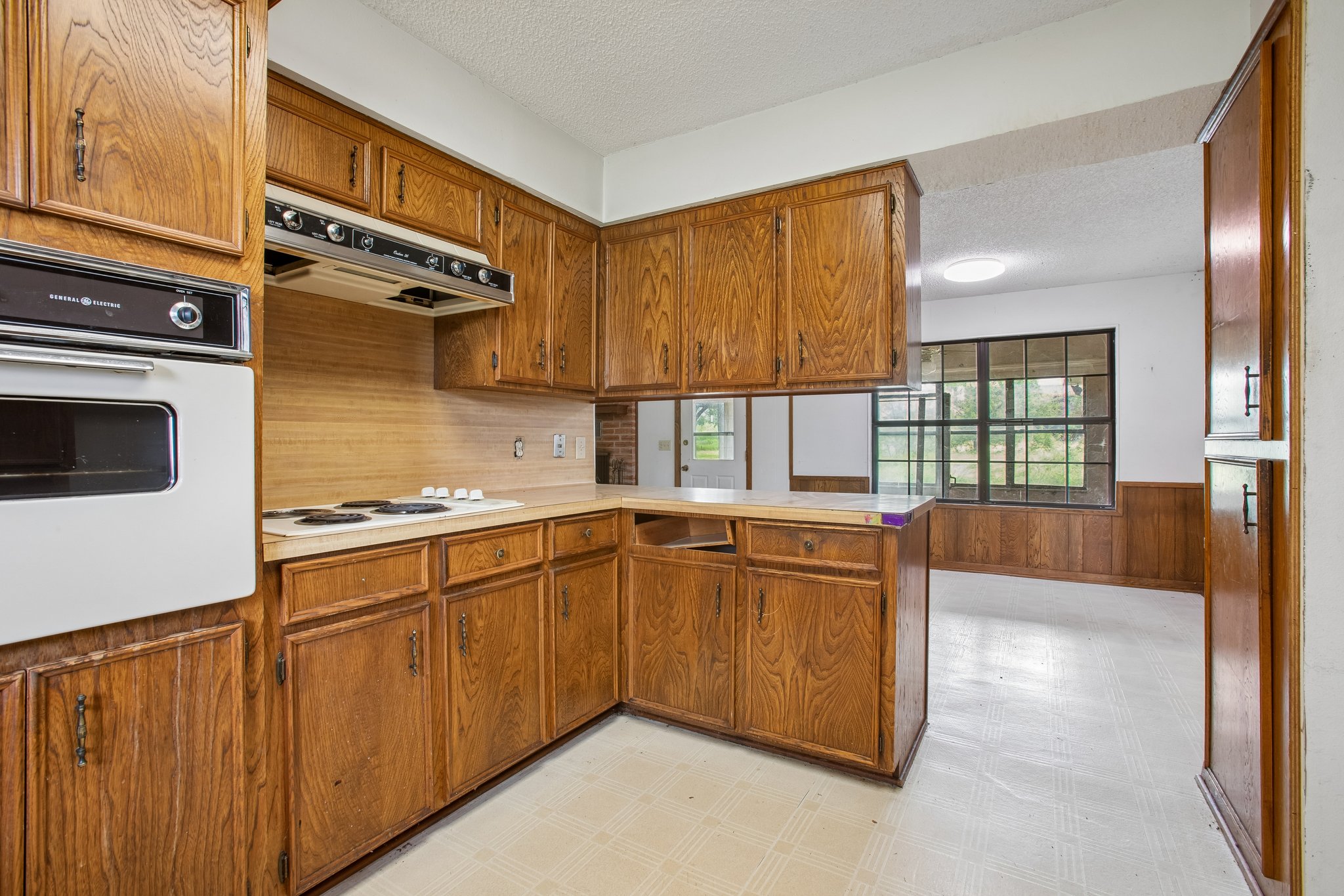 406 Monkey Road Elgin, TX 78621 - Photo 11 of 39 Kitchen featuring wood cabinetry, white wall oven, electric cooktop, and a matching range hood